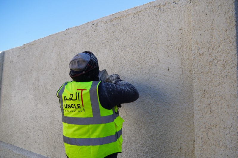 An Uncle T worker plastering a school wall